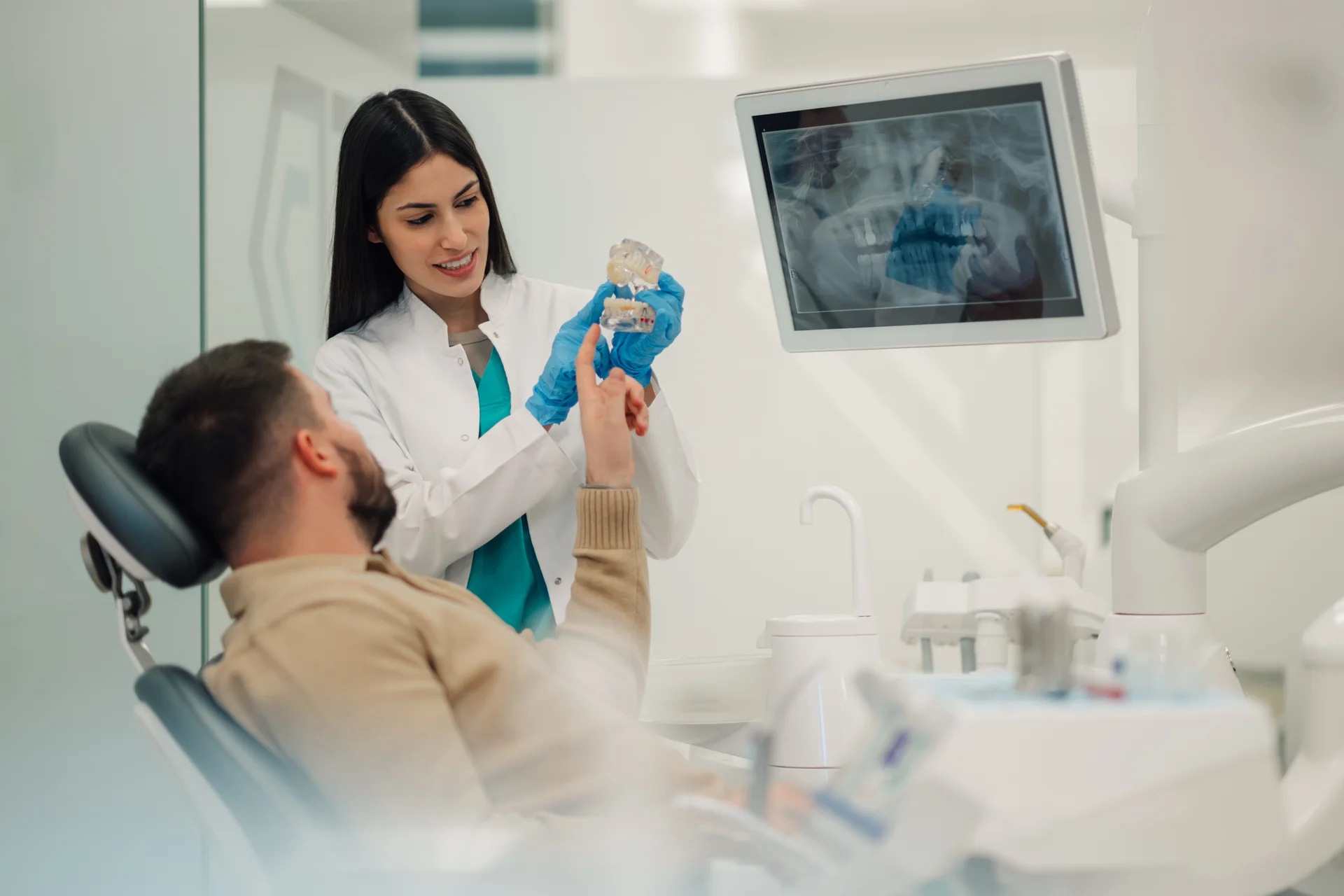 Patient smiling while a dentist points to healthy teeth