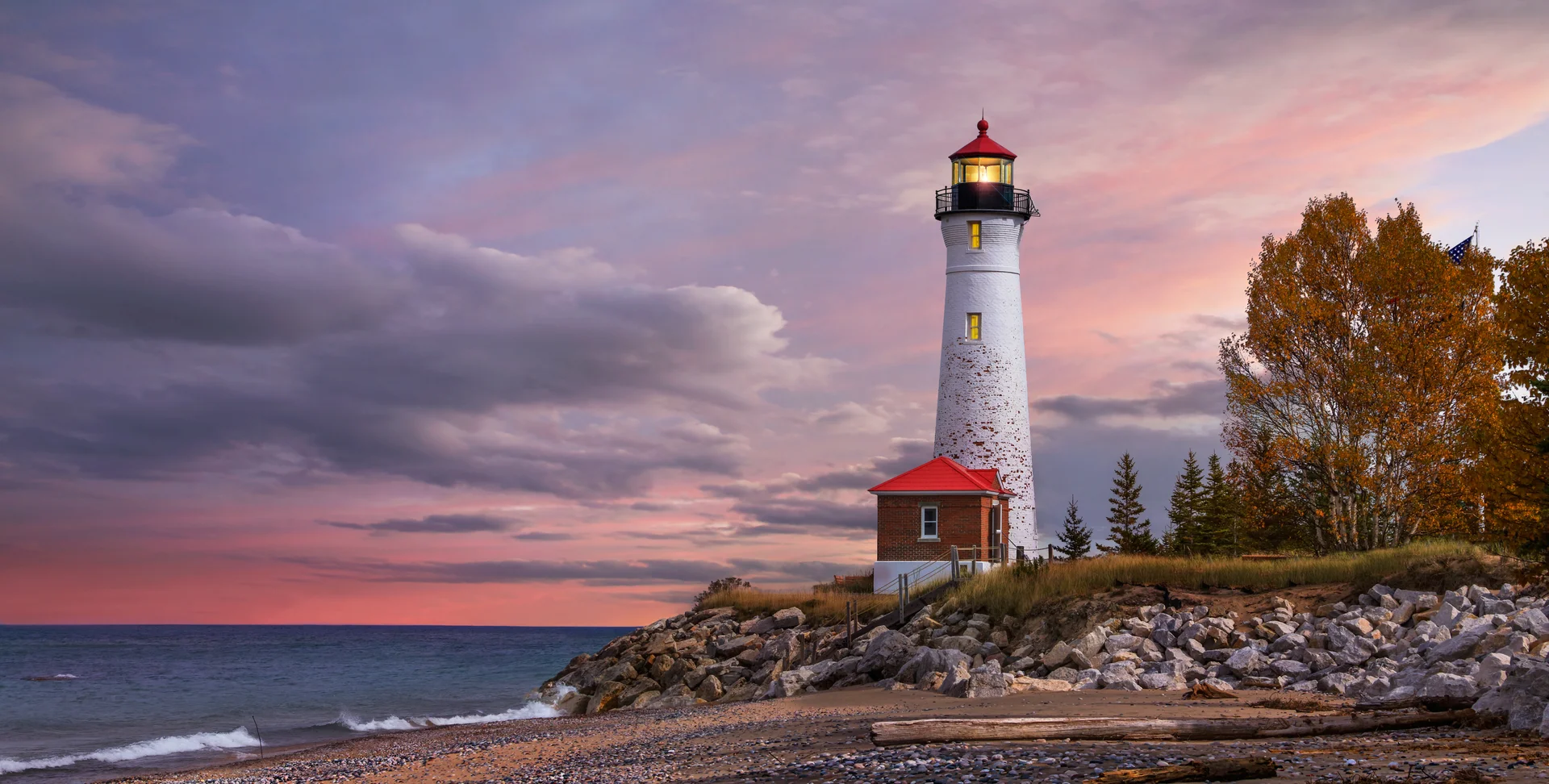 Lighthouse on the rocky New England coast at sunset
