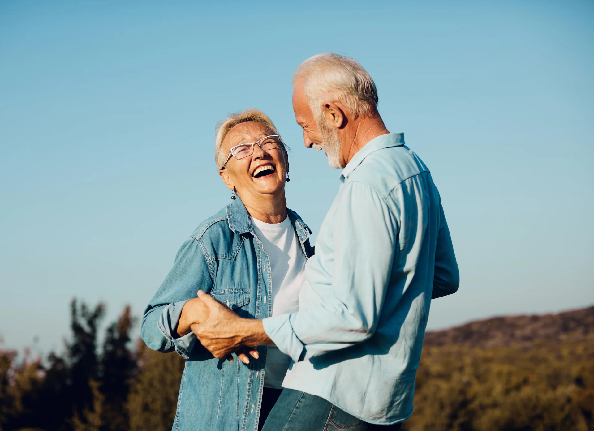 Happy couple laughing outdoors with natural healthy smiles