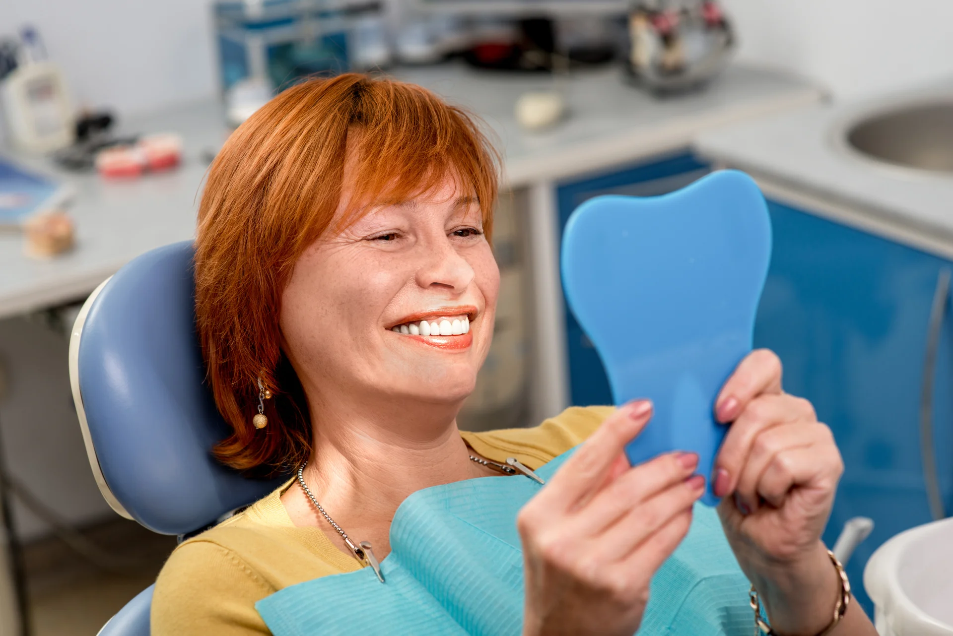 Smiling patient checking her new smile in a hand mirror