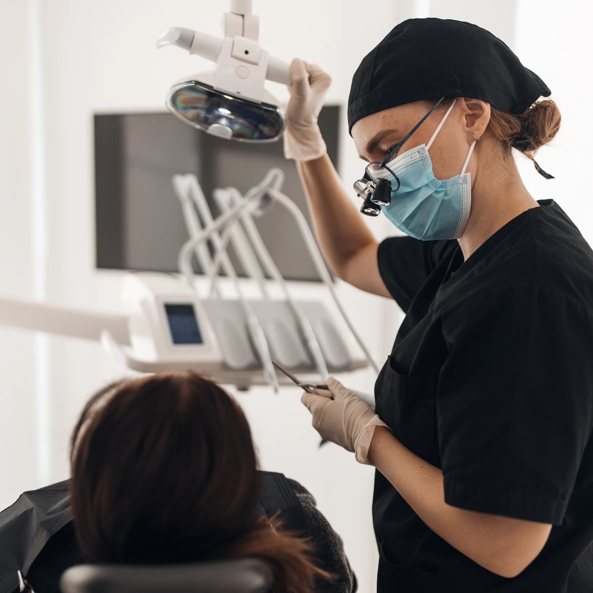 Smiling patient holding a blue mirror and viewing his new smile with his dentist